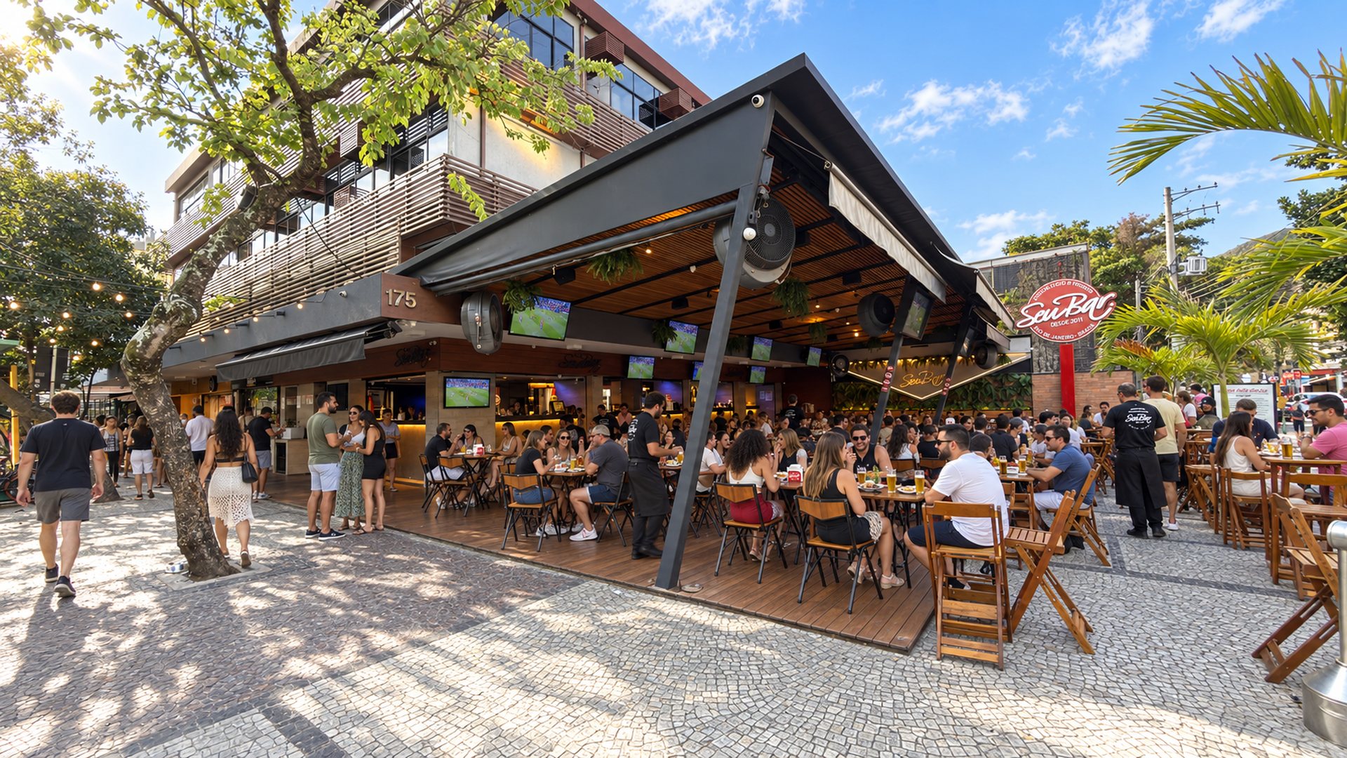 Fachada do Seu Bar na Av. Olegário Maciel, 175, Jardim Oceânico, Barra da Tijuca: deck de madeira na calçada com as mesas cheias no fim da tarde